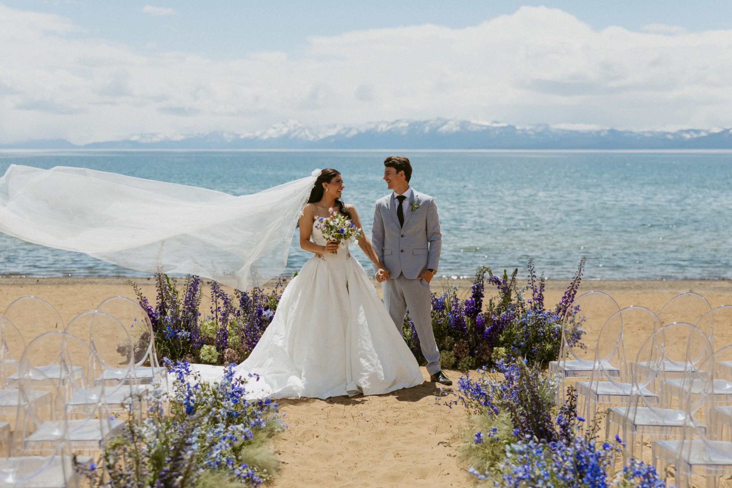 Lake Tahoe beach wedding: bride with veil blowing in the wind, blue delphinium ceremony aisle at Kings Beach