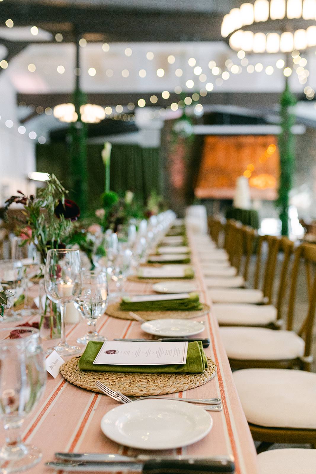 Long reception table at Palisades High Camp under string lights, set with garden roses, olive foliage and green velvet napkins